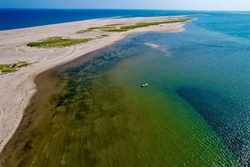 Aerial view of a sandy inlet and shallow green water