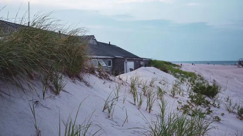 Weathered cottage behind a sand dune